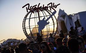 Foto da cidade do rock ao entardecer com o globo e o símbolo do Rock in Rio em contraluz com o pôr do sol