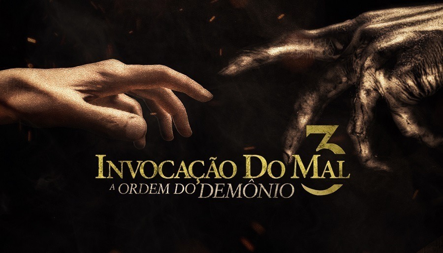 cartaz de A Invocação do Mal 3com uma mão humana quase tocando uma mão demoníaca, sob um fundo preto com o nome do filme em dourado