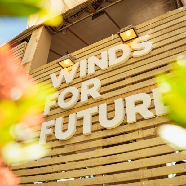 Logotipo da Winds for Future em uma parede de madeira com flores