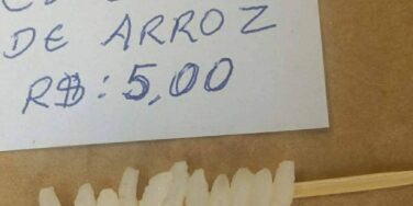 memes do preço do arroz: grãos de arroz espetados em um palito de dente com um aviso dizendo "espetinho de arroz R$5,00"