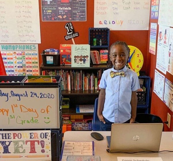 Menino Bryce em sua sala de aula montada em casa, com posteres, uma biblioteca pequena, laptop e cartazes