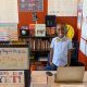 Menino Bryce em sua sala de aula montada em casa, com posteres, uma biblioteca pequena, laptop e cartazes