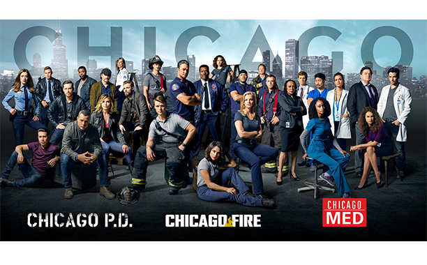 Elenco das séries Chicago PD, Chicago Fire e Chicago Med lado a lado com a palavra Chicago escrita no topo e, ao fundo, imagens de prédios